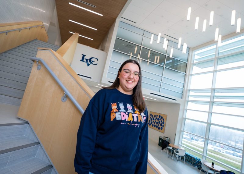 Angele, a childhood cancer survivor and pediatric oncology nurse, stands inside Penn State Health Golisano Children’s Hospital.