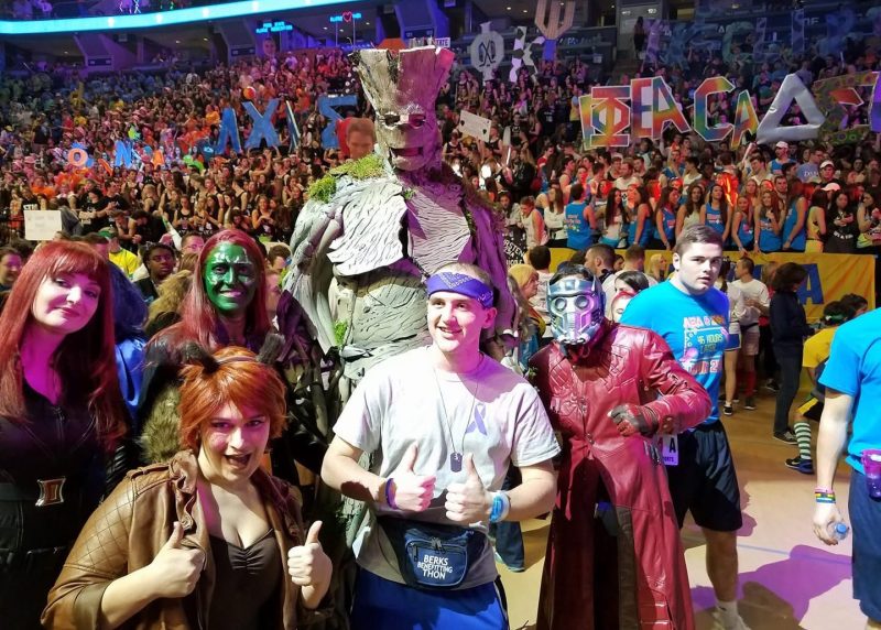 Tyler smiles with Marvel-themed volunteers and performers during THON, surrounded by students and supporters inside the Bryce Jordan Center.