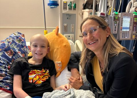 Asher smiles from his hospital bed alongside Dr. Sholler during treatment for childhood neuroblastoma.