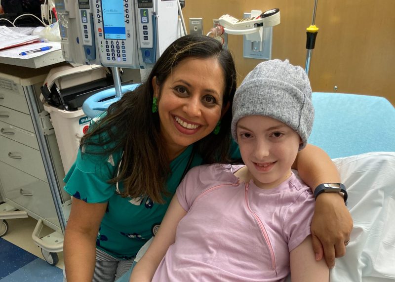 Four Diamonds child Daisy smiles with a member of her care team during childhood cancer treatment.