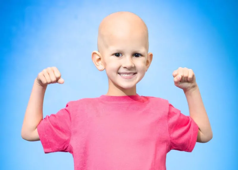 Four Diamonds child Presley smiles and flexes her arms during treatment for a Wilms tumor.