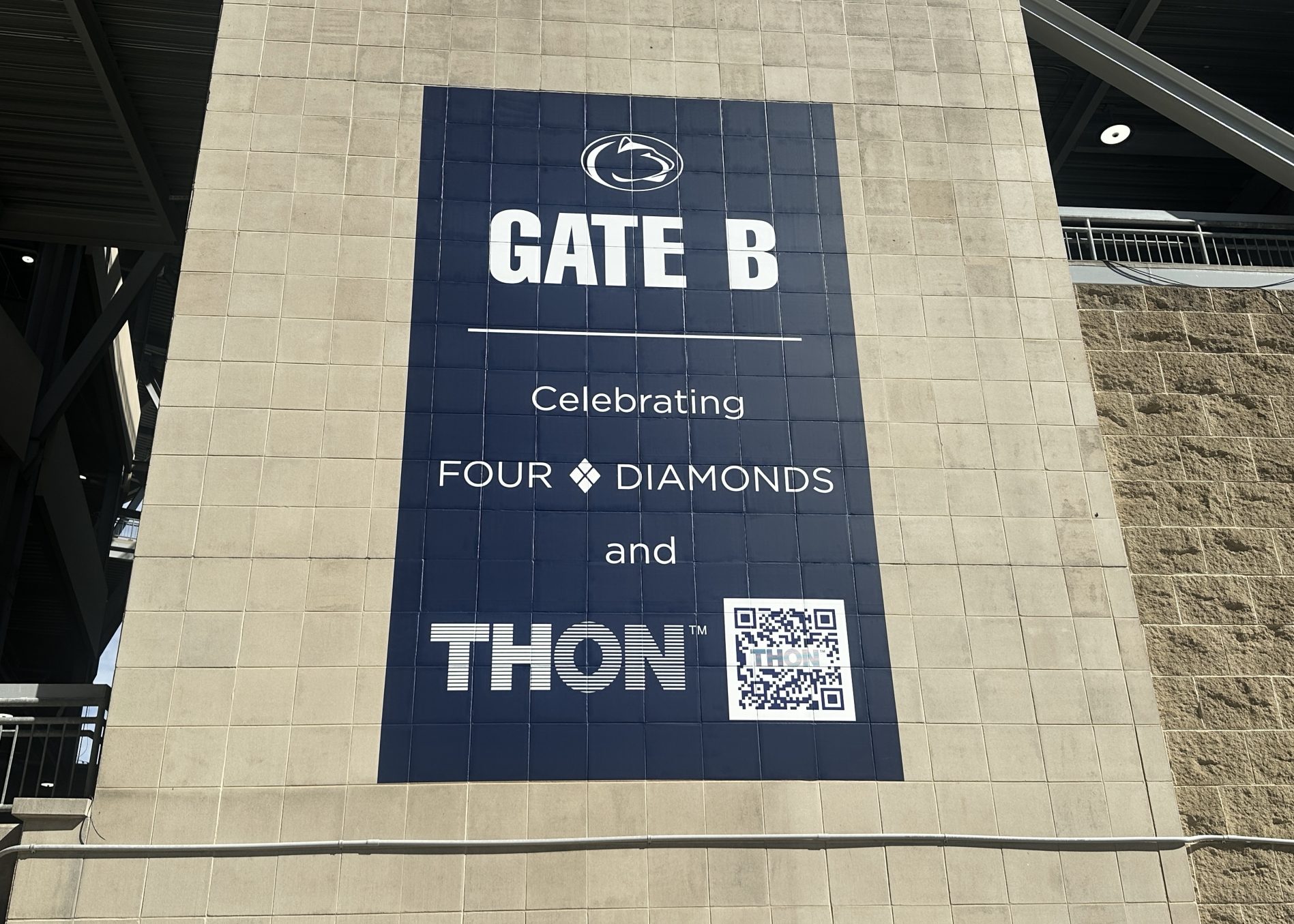 Penn State Gate B displays a banner celebrating Four Diamonds and THON, featuring both organizations’ logos and a QR code.
