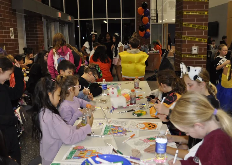 Children in Halloween costumes color and participate in activities around a table during Lower Moreland High School Mini-THON's Kids' Night Out.