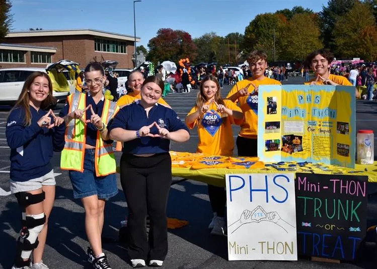 Palmyra Area High School Mini-THON students pose behind a decorated Trunk or Treat table featuring signs, candy and Four Diamonds materials.